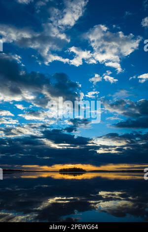 Erstaunlich schöner Sonnenaufgang über dem Malarsee in Schweden, ruhiges Wasser reflektiert den Himmel mit dramatischen Wolken, die von der Sonne beleuchtet werden, hellgelber Horizont mit d Stockfoto