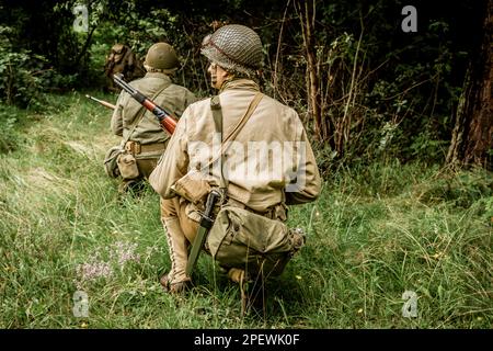 Porabka, Polen – July18, 2020 : Historische Reeneaktoren, die während des Zweiten Weltkriegs als amerikanischer Infanterie-Soldat verkleidet waren, patrouillieren den Wald. Ansicht vom Stockfoto