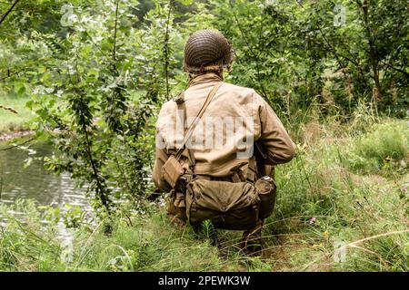 Porabka, Polen – July18, 2020 : Historischer Reeneaktor, gekleidet als amerikanischer Infanterie-Soldat während des Zweiten Weltkriegs, patrouilliert den Wald. Blick aus dem B Stockfoto