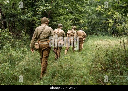 Porabka, Polen – July18, 2020 : Historische Reeneaktoren, die während des Zweiten Weltkriegs als amerikanischer Infanterie-Soldat verkleidet waren, patrouillieren den Wald. Ansicht vom Stockfoto