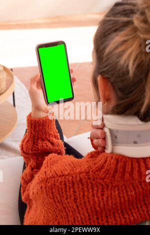 Nicht wiedererkennbare Frau mit Halskragen am Hals, die Probleme mit dem Arzt diskutiert, während sie während einer Online-Sitzung ein Videogespräch mit dem Smartphone führt Stockfoto