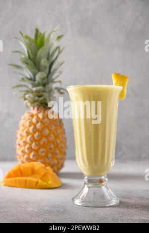 Asiatische Ananas und Mango, Smoothie auf grauem Hintergrund. Beliebtes Frischgetränk mit Joghurt, Wasser, Obst und Eis in Indien und Sri lanka. Vert Stockfoto