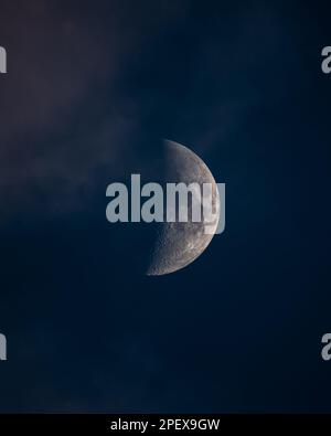 Ein großer Halbmond, teilweise verdeckt von Wolken am Nachthimmel mit verschwommenem Hintergrund Stockfoto