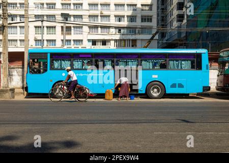 Yangon, Myanmar - 19. Dezember 2019: Ein Mann fährt mit dem Fahrrad an einem blauen Bus vorbei, der auf der Seite der Merchant Rd, Rangun (Yangon), Birma, Myanmar, geparkt ist Stockfoto