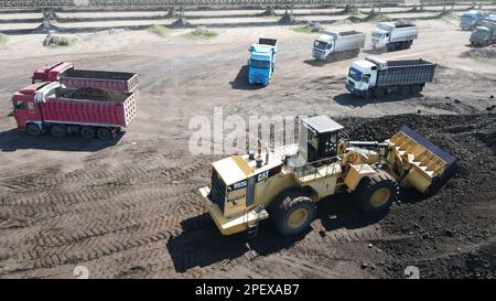 Radlader, der Kohle auf Lkw lädt und auf einer riesigen Bergbaustelle arbeitet. Stockfoto