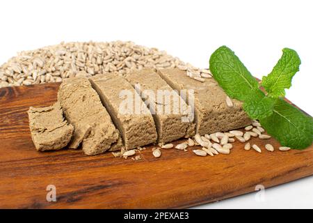 Halva-Stücke auf Holzschneidplatte isoliert, Sonnenblume Halawa, Halvah oder Halwa auf weißem Hintergrund Stockfoto