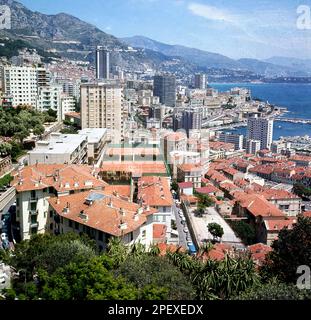 1960er, historisch, französische Riviera, Sommer und Blick auf die Terrakotta Dächer von Monaco, mit den luxuriösen Apartmentblöcken des Monte Carlo und seinem Hafen im Mittelmeer in der Ferne. Stockfoto