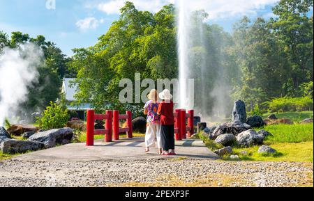 Zwei nicht identifizierbare Personen stehen vor der heißen Quelle in San Kamphaeng Springs, Thailand. Stockfoto