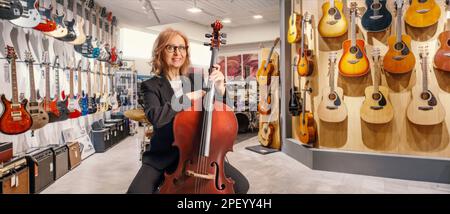 Eine Frau mit Cello, die in einem Musikgeschäft sitzt Stockfoto