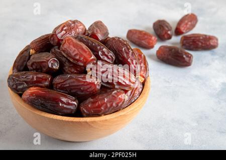 Datteln Sie Früchte in einer Holzschüssel auf hellem Hintergrund Stockfoto