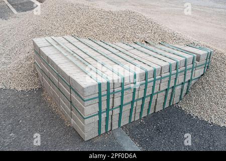 Bordsteine aus Beton Cinder, graue uniformierte Ziegelform. Baumaterial gestapelte Pflastersteine Neu für den Einsatz auf der Straße Stockfoto