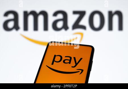 In dieser Abbildung wird das Amazon Pay-Logo auf einem Smartphone und im Hintergrund das Amazon-Logo angezeigt. Stockfoto