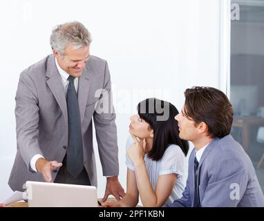 Er gab ihnen seinen angesehenen Rat. Ein Geschäftsführer, der seine beiden jüngeren Kollegen bei einem Meeting berät. Stockfoto