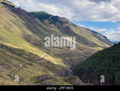 Panorama einer Straße auf einem Hügel entlang eines Berges unter Wolken und eines Flusses mit Felsen in Altai in Sibirien Stockfoto