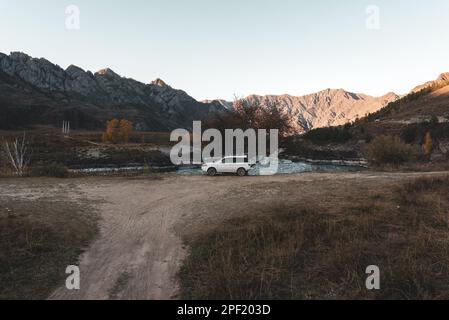 Abends steht in Altai in Sibirien eine alte Autokarke „Honda HR-V“ in der Ferne der Straße unter den Bergen und Felsen in der Nähe des Flusses. Alta Stockfoto