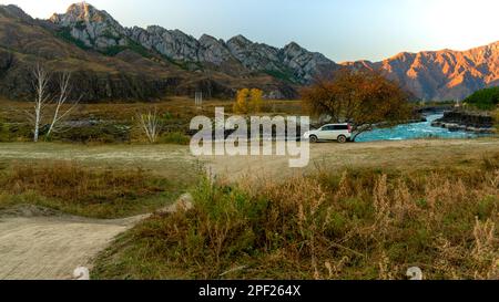 Ein altes Crossover-Auto der Marke „Honda HR-V“ steht an der Straße unter einem Baum in der Nähe der Berge in der Nähe des Flusses in Altai in Sibirien. Altai, Russland - Oktober Stockfoto