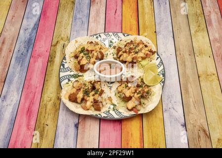 Wundervolle mexikanische knusprige Fisch-Tacos auf einem schönen Teller mit Maistortillas, Limettenspalten und Salsa Stockfoto