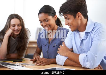 Die Ideen fließen. Drei junge Kollegen, die an einem Schreibtisch arbeiten. Stockfoto