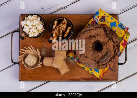 Holzteller mit Kuchen, Popcorn, Paecoquinha und pé de Moleque - Juni-Party. Stockfoto