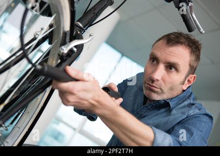 Konzentrierter Mann, der die Reifen auf seinem Fahrrad hochpumpt Stockfoto