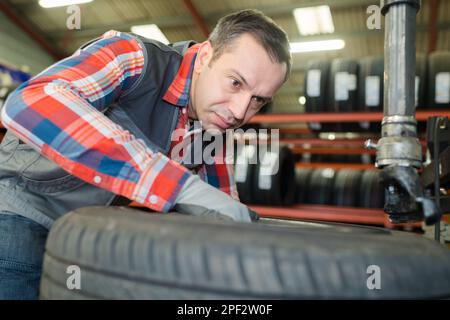 Professioneller Automechaniker wuchtet Autorad aus Stockfoto