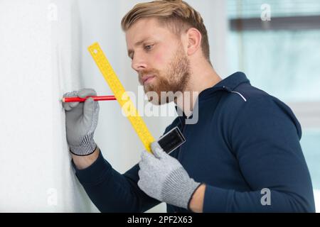 Männlich in Handschuhen, Wandmessung mit Band Stockfoto