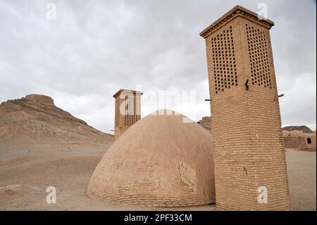 Wind Türmen als eine natürliche Kühlung für Wasserbehälter in der iranischen traditionellen Architektur verwendet. Turm des Schweigens im Hintergrund. Yazd, Iran Stockfoto