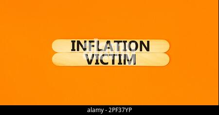 Symbol für Inflationsopfer. Konzeptbegriffe Inflationsopfer auf Holzstöcken. Schöner orangefarbener Tischhintergrund. Das Konzept der Inflationsopfer von Unternehmen. Stockfoto