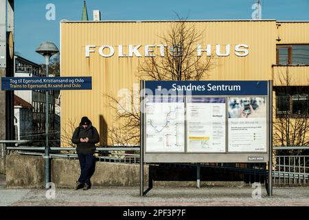 Sandnes, Norwegen, März 10 2023, Mann steht alleine auf Einem Bahnhofsstand mit einem Mobiltelefon Stockfoto