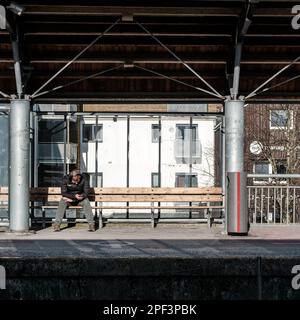 Sandnes, Norwegen, März 10 2023, Mann Sitzt Allein Auf Bahnhofsplattform Und Benutzt Handy Warten Auf Zug Stockfoto
