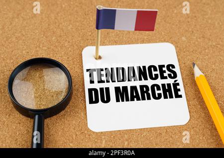 Auf dem Tisch liegt die Fahne Frankreichs, ein Bleistift, eine Lupe und ein Blatt Papier mit einer Inschrift auf Französisch, die ins Englische übersetzt wird als... Stockfoto