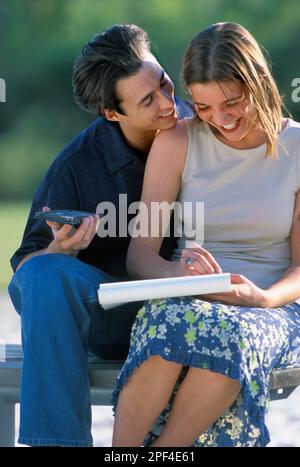 Ein romantisches Paar, das Spaß hat, auf einer Parkbank zu sitzen Stockfoto