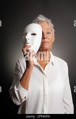 Ernsthafte Suche reife Frau zeigt wahres Gesicht hinter der Maske Stockfoto