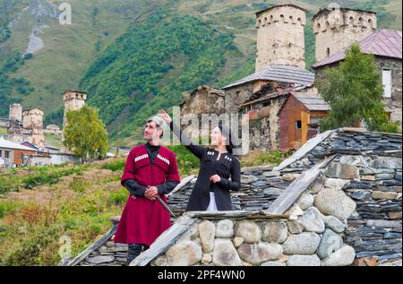 Georgisches Paar aus einer Folkloregruppe auf einer Steinbrücke außerhalb des Dorfes Ushguli, nur zu redaktionellen Zwecken, Ushguli, Svaneti-Region, Georgien Stockfoto