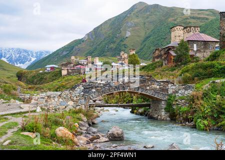 Georgisches Paar aus einer Folkloregruppe auf einer Steinbrücke außerhalb des Dorfes Ushguli, nur zu redaktionellen Zwecken, Ushguli, Svaneti-Region, Georgien Stockfoto