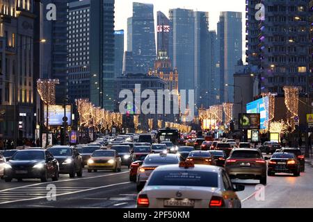Autos stehen im Stau auf der Novy Arbat Straße in der Innenstadt. Blick auf die Wolkenkratzer von Moskau und Lichter am Abend Stockfoto