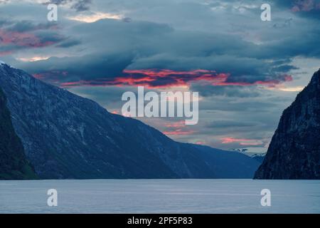 Norwegen, Blick auf einen Teil des Südfjords am Abend kurz nach Sonnenuntergang, kontrastierende Wolkenschichten, deren Unterseiten teilweise beleuchtet sind Stockfoto