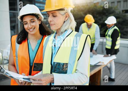 Ich delegiere. Zwei Auftragnehmer stehen zusammen draußen und führen eine Diskussion über ein Klemmbrett. Stockfoto