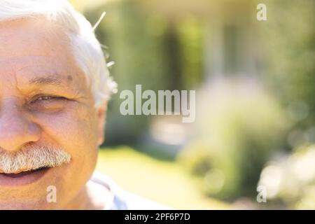 Porträt eines glücklichen, birassischen Seniorenmannes, der im Garten vor die Kamera schaut Stockfoto