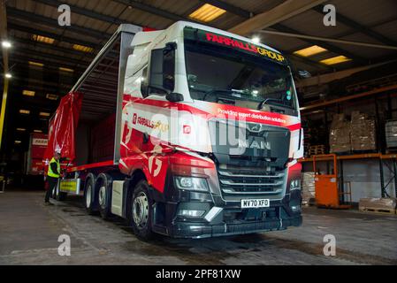 EIN MANN-Truck mit einem Anhänger mit Schiebeplanenaufbau, der in einem Lagerhaus verladen wurde Stockfoto