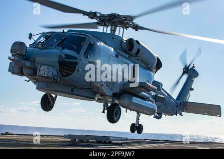 230312-N-LK647-1216 ATLANTISCHER OZEAN (12. März 2023) ein MH-60R Seahawk-Hubschrauber startet vom Cockpit des geführten Raketenkreuzers der Ticonderoga-Klasse USS Normandy (CG 60), während das Schiff Flugquartiere führt, 12. März 2023. Die Ford Carrier Strike Group führt derzeit im Atlantik ihre Composite Training Unit Exercise (COMPTUEX) durch, eine intensive, mehrwöchige Übung, die darauf abzielt, eine Trägerstreikgruppe als zusammenhängende, multimissionale Kampftruppe vollständig zu integrieren und ihre Fähigkeit zur Durchführung nachhaltiger Kampfoperationen vom Meer aus zu testen. Als erstklassiges Schiff der for Stockfoto