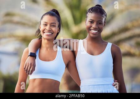 Tennis ist ein feines Gleichgewicht zwischen Entschlossenheit und Müdigkeit. Zwei attraktive Frauen stehen zusammen, während sie draußen Tennis spielen. Stockfoto