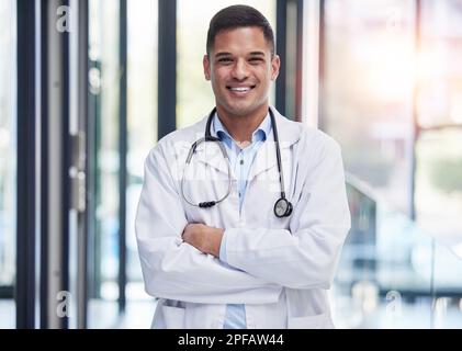 Porträt, Mann Arzt und Lächeln mit gekreuzten Armen, Selbstvertrauen und professionelle Medizin im Krankenhaus. Glückliche junge Pflegekraft im Laborkittel, medizinisch Stockfoto