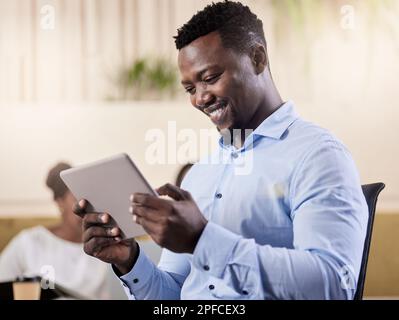 Meine E-Mails durchgehen. Ein junger Geschäftsmann, der sein digitales Tablet während der Arbeit verwendet. Stockfoto