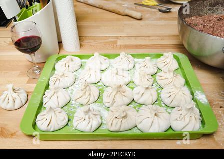 Khinkali: Georgianische Knödel auf einer grünen Kunststoffschale, die in heißem Wasser gekocht werden können Stockfoto