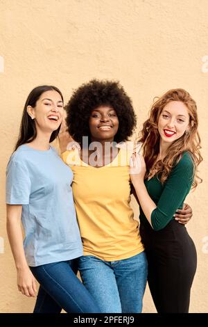 Vertikales Porträt von drei multiethnischen Freunden, die vor der Kamera lächeln Stockfoto