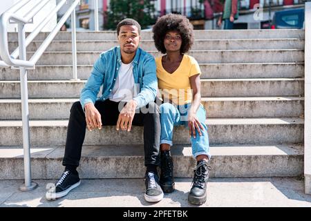 Stilvolle afrikanische Freunde, die auf der Treppe auf der Straße sitzen Stockfoto