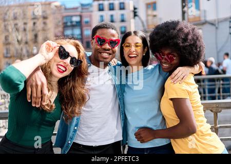 Multiethnische Freunde, die Spaß mit einer herzförmigen Sonnenbrille haben Stockfoto