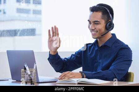 Telekommunikation erhöht die Flexibilität am Arbeitsplatz. Ein junger Geschäftsmann, der ein Headset trägt, während er ein Notebook im Büro verwendet. Stockfoto