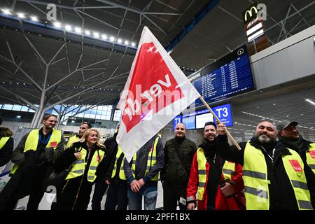 Stuttgart, Deutschland. 17. März 2023. Streikende Mitarbeiter des Stuttgarter Flughafens stehen mit Westen der Gewerkschaft Verdi in der leeren Abflughalle des Stuttgarter Flughafens. Flüge wurden wegen eines Verdi-Streiks gestrichen. Kredit: Bernd Weißbrod/dpa/Alamy Live News Stockfoto